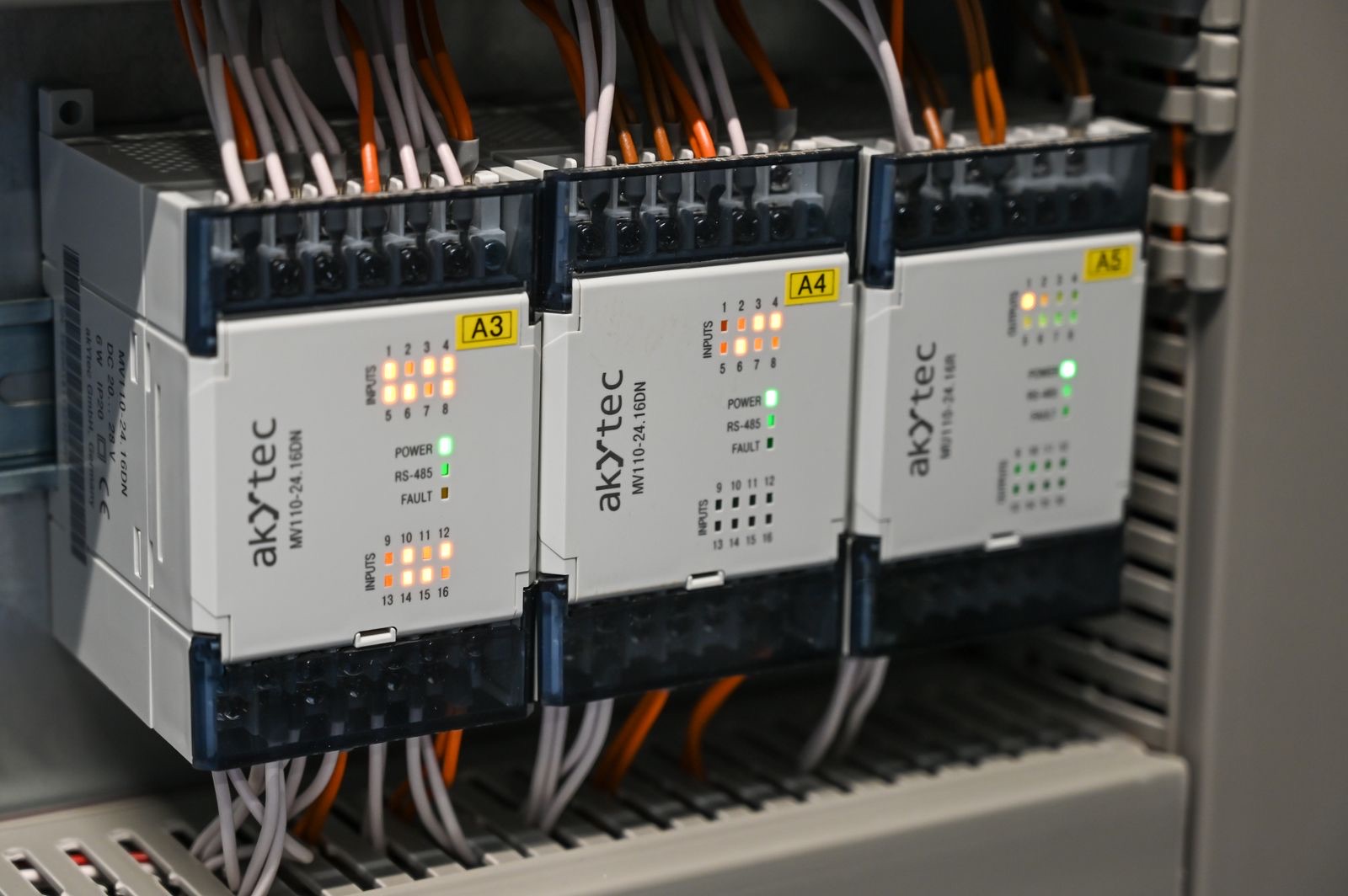 DIN-rail RS-485 I/O modules wired in an industrial control cabinet with status LEDs lit