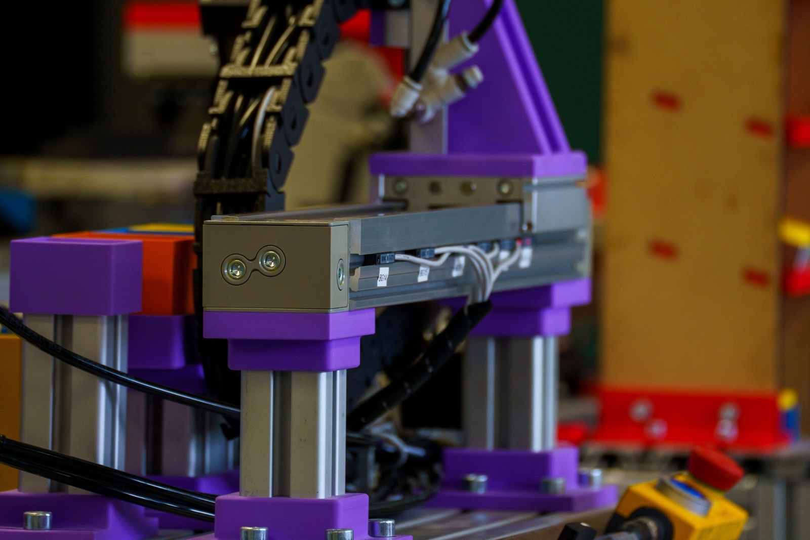 3D-printed robotics rig with linear actuators and cable chains on a workshop bench